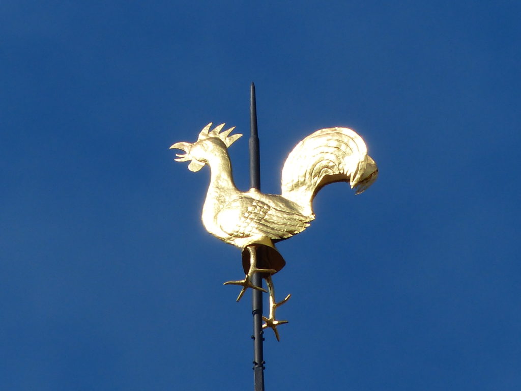 Goldener Wetterhahn vor tiefblauem Himmel