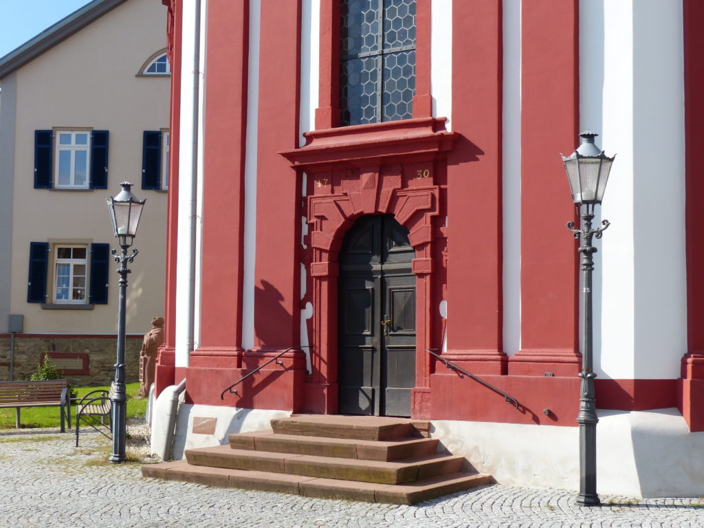 Kirchenportal mit Laurentius und Pfarrhaus