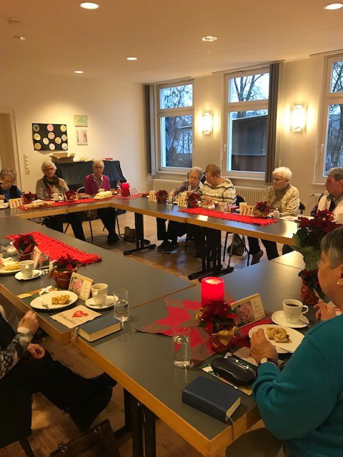 Mehrere Frauen sitzen an weihnachtlich geschmückten Tischen