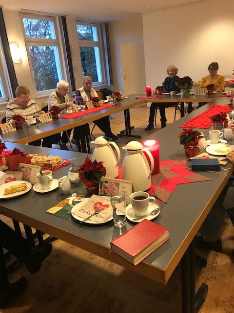 Mehrere Frauen sitzen an weihnachtlich geschmückten Tischen