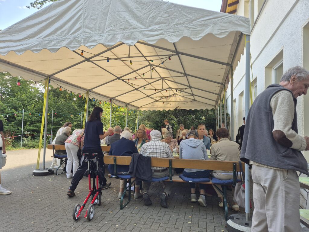 Menschen auf dem Gemeindehausvorplatz bei Kaffee und Kuchen