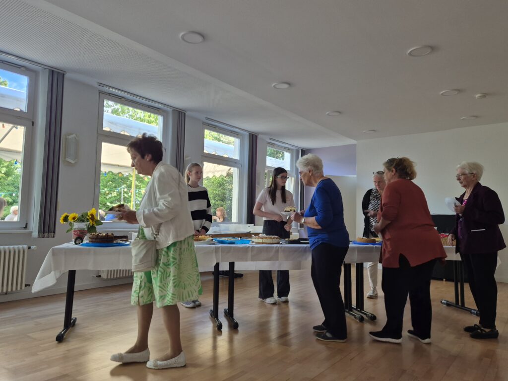 Menschen auf dem Gemeindehausvorplatz bei Kaffee und Kuchen