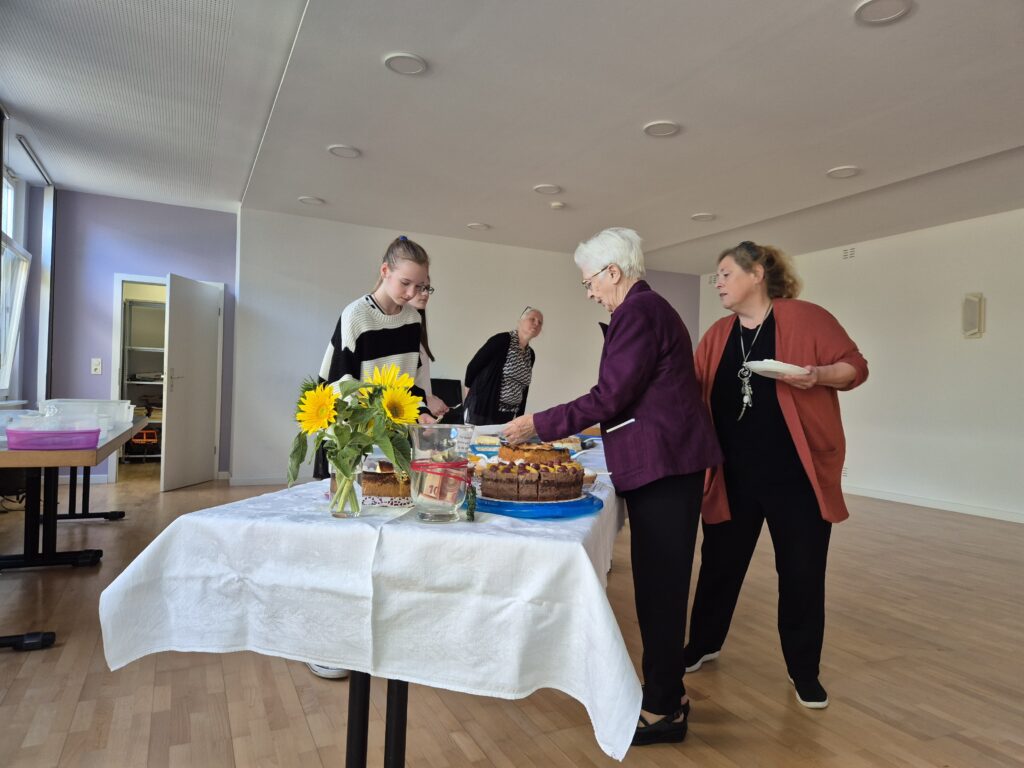 Menschen auf dem Gemeindehausvorplatz bei Kaffee und Kuchen