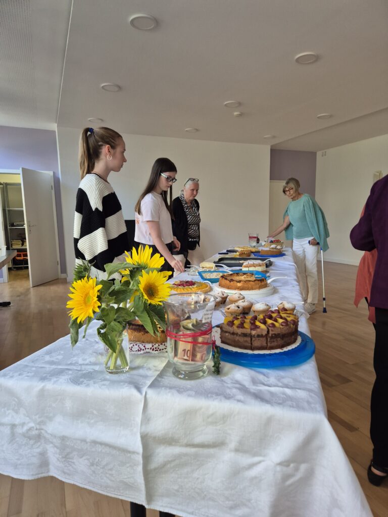Menschen auf dem Gemeindehausvorplatz bei Kaffee und Kuchen