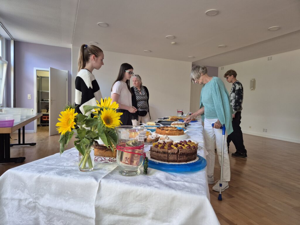 Menschen auf dem Gemeindehausvorplatz bei Kaffee und Kuchen