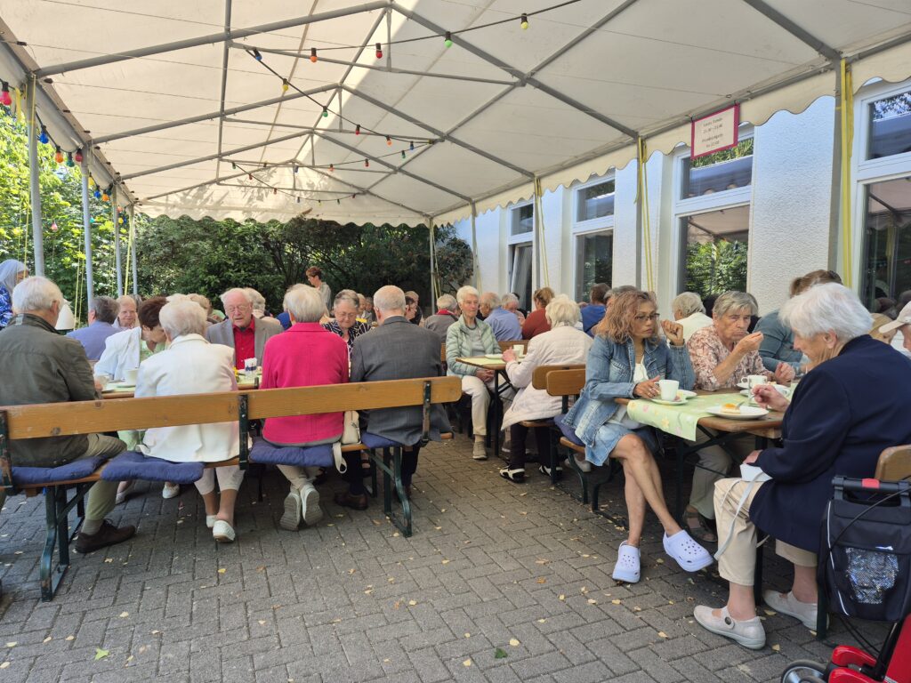 Menschen auf dem Gemeindehausvorplatz bei Kaffee und Kuchen