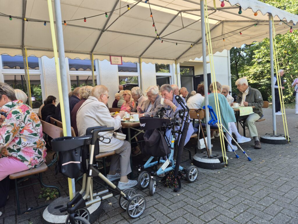 Menschen auf dem Gemeindehausvorplatz bei Kaffee und Kuchen