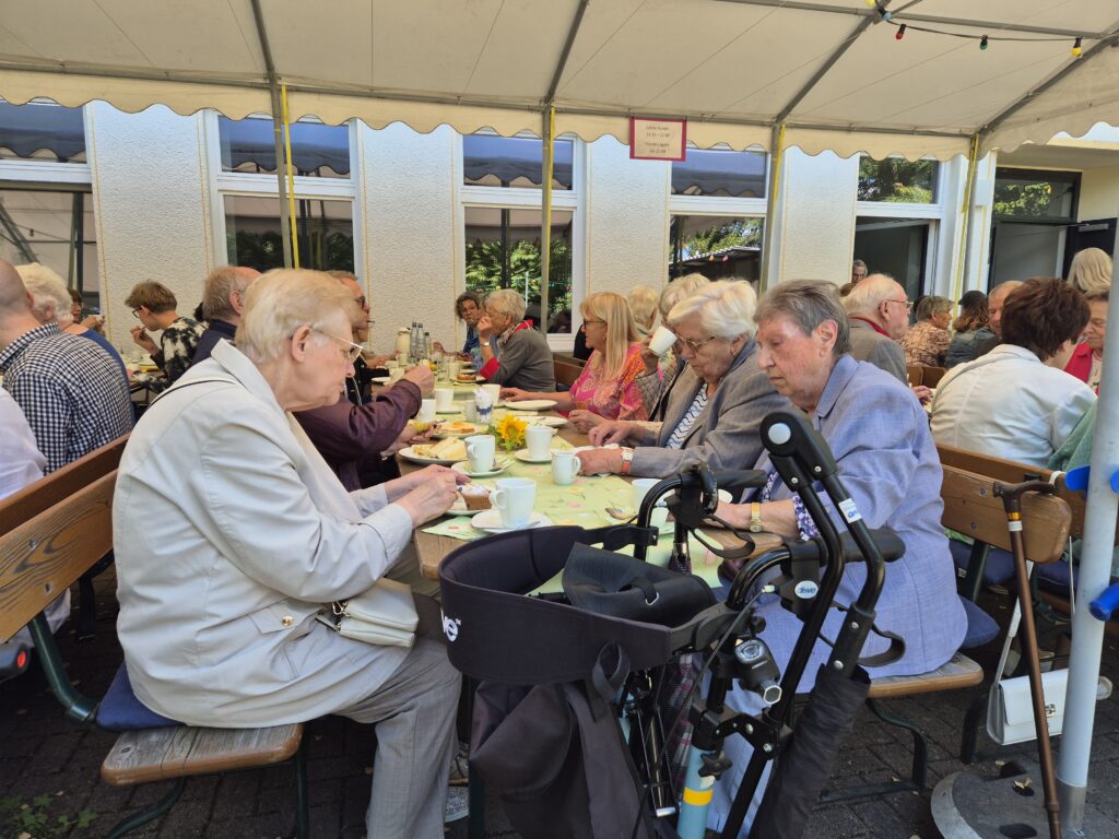 Menschen auf dem Gemeindehausvorplatz bei Kaffee und Kuchen