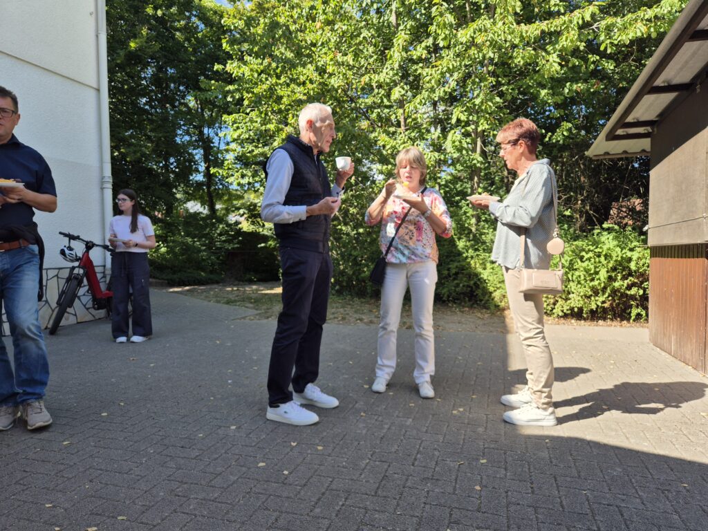 Menschen auf dem Gemeindehausvorplatz bei Kaffee und Kuchen