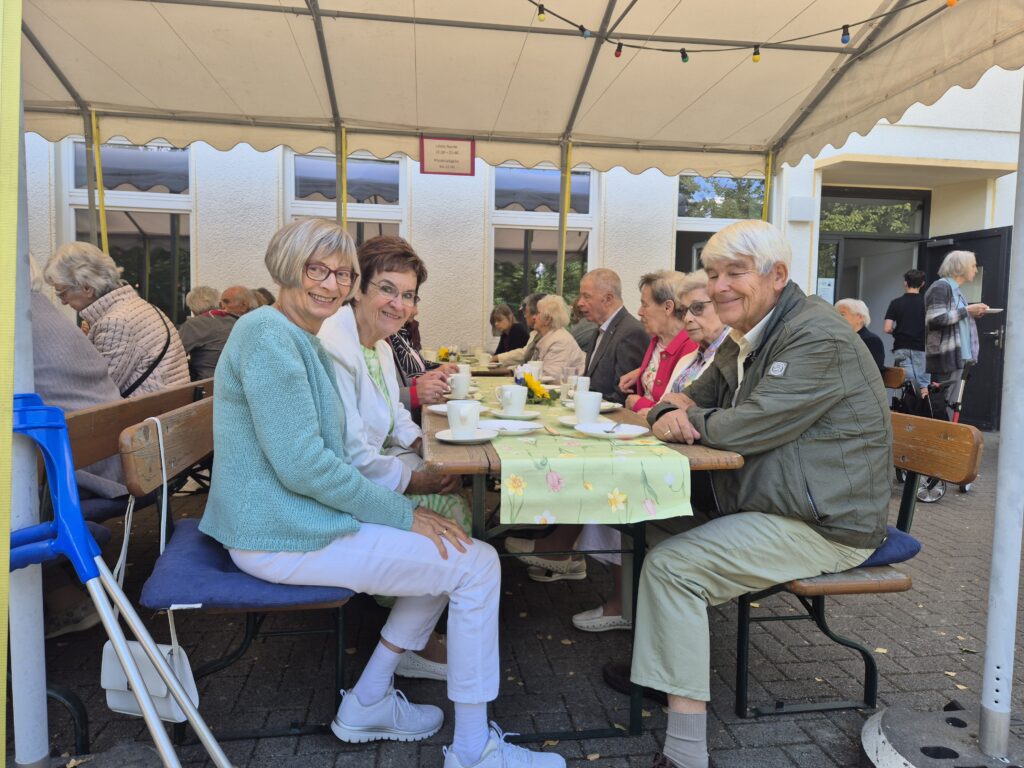 Menschen auf dem Gemeindehausvorplatz bei Kaffee und Kuchen