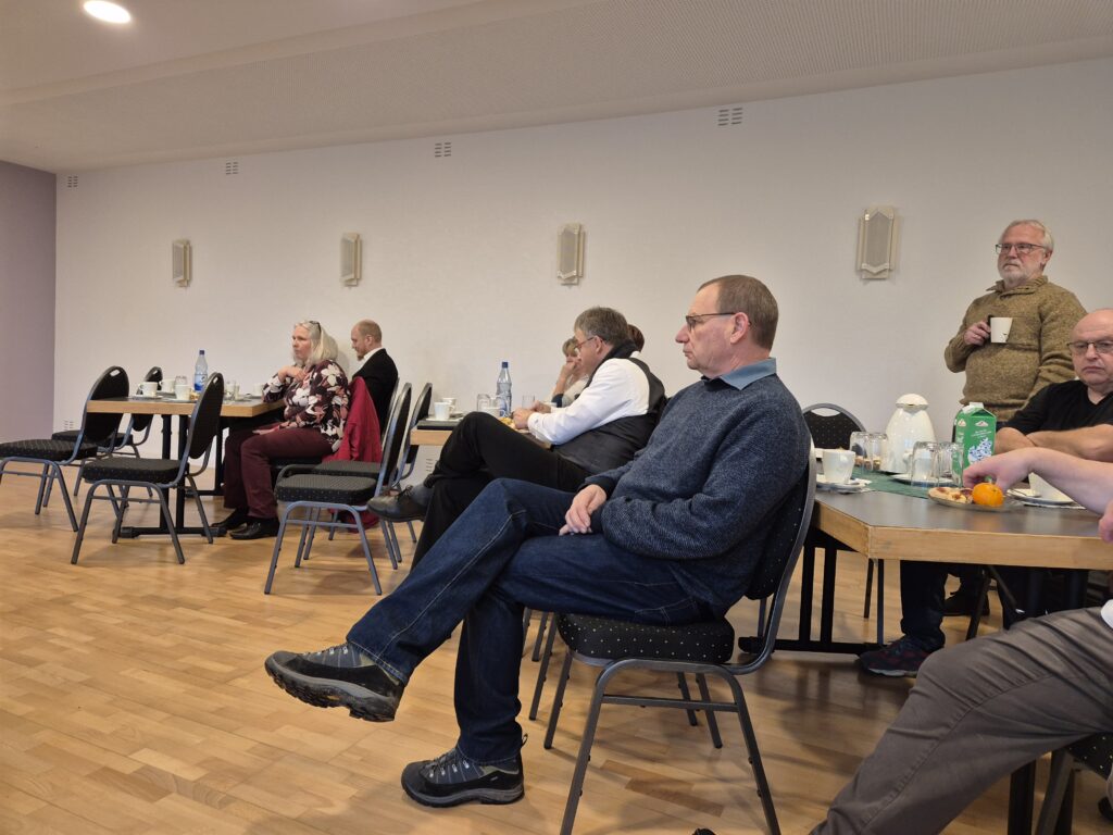 Menschen, die in einem Raum sitzen und der redenden Person zuhören