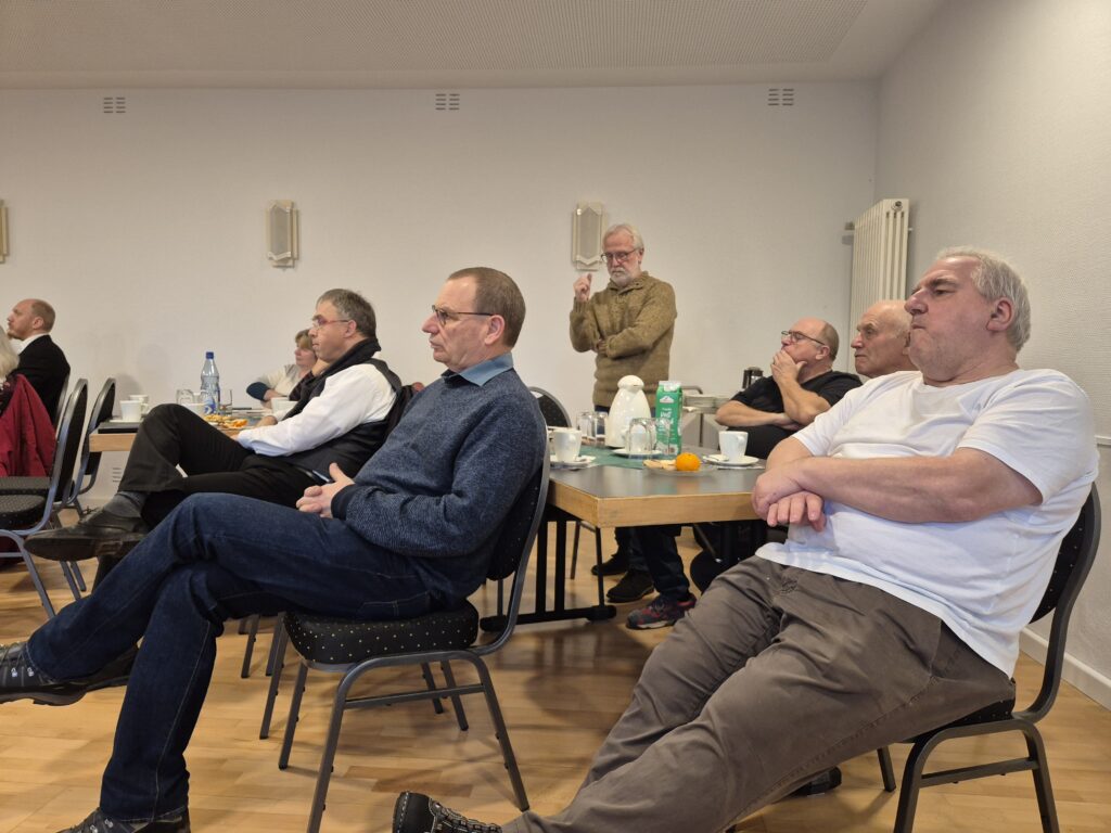 Menschen, die in einem Raum sitzen und der redenden Person zuhören