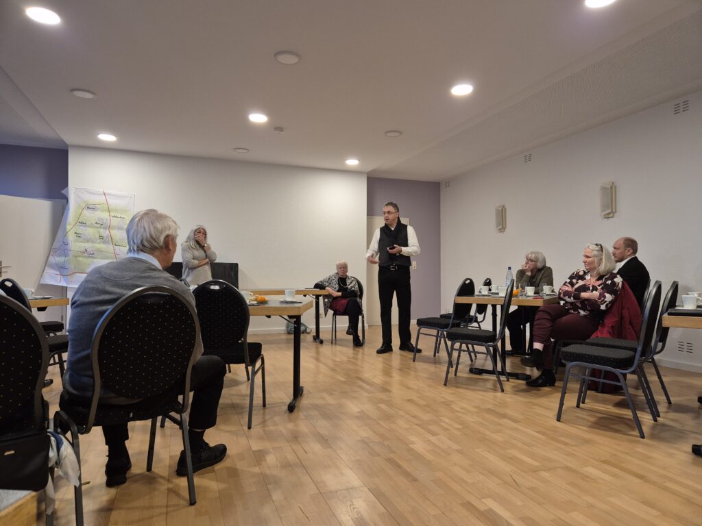 Menschen, die in einem Raum sitzen und der redenden Person zuhören