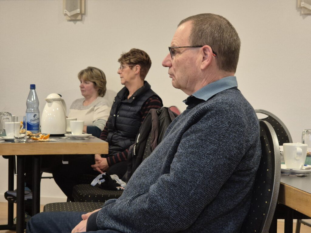 Menschen, die in einem Raum sitzen und der redenden Person zuhören