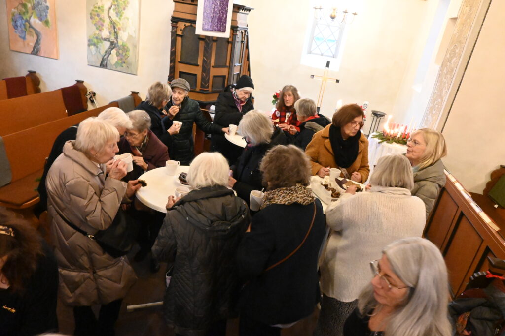 Menschen stehen zusammen mit Kaffee und Plätzchen