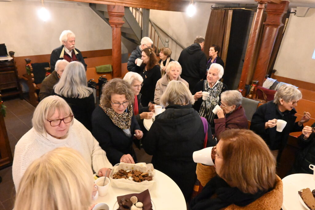 Menschen stehen zusammen mit Kaffee und Plätzchen