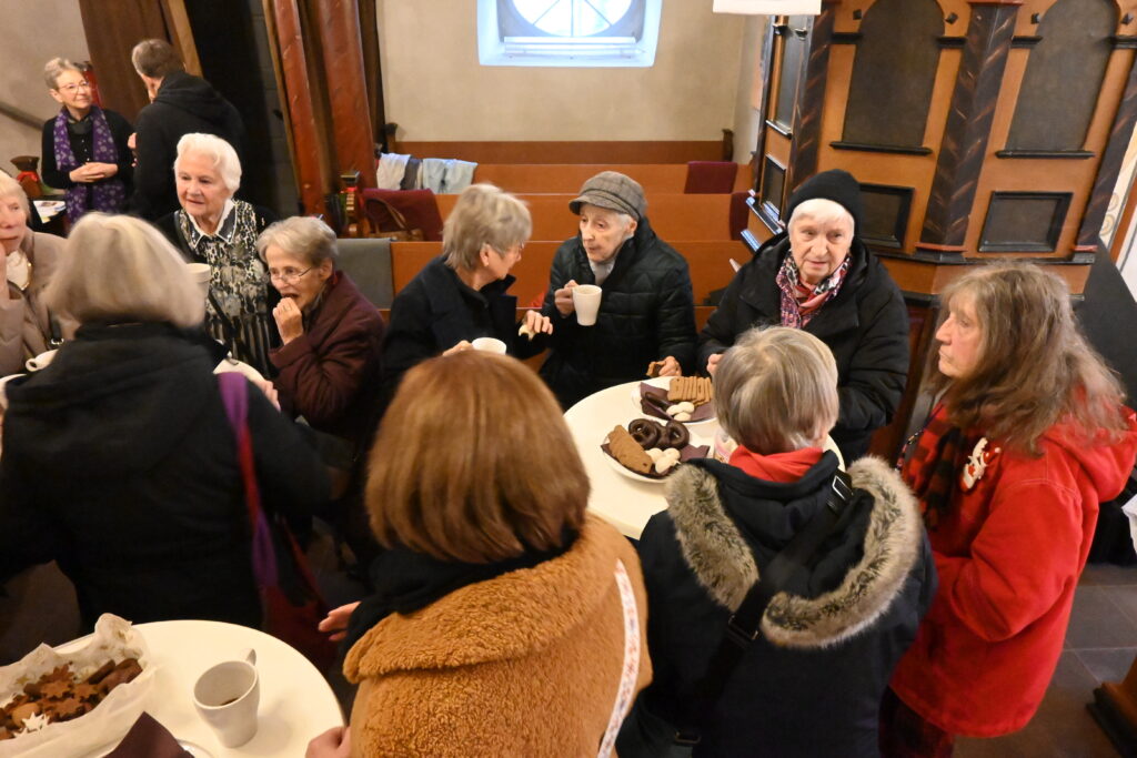 Menschen stehen zusammen mit Kaffee und Plätzchen