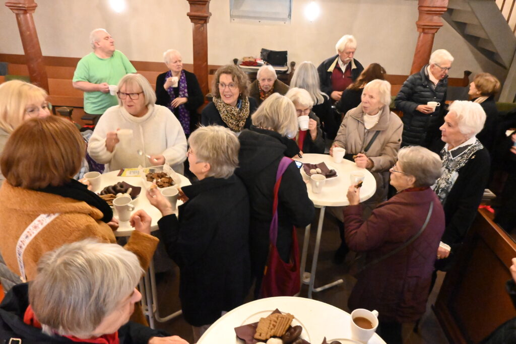 Menschen stehen zusammen mit Kaffee und Plätzchen