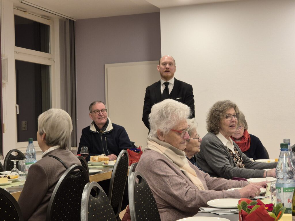 Mehrere Menschen sitzen an Tischen und essen. 