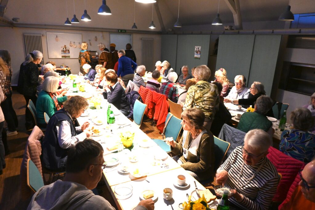 Menschen an langen Tischen beim Essen