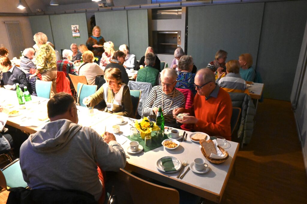 Menschen an langen Tischen beim Essen