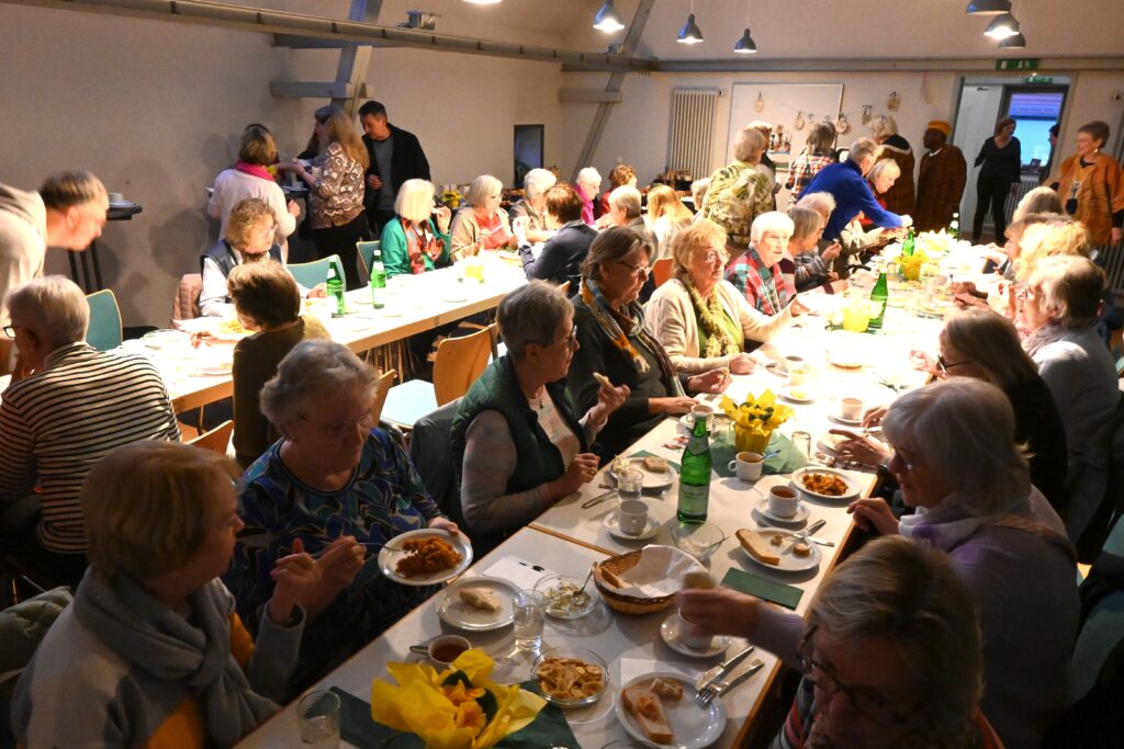 Menschen an langen Tischen beim Essen