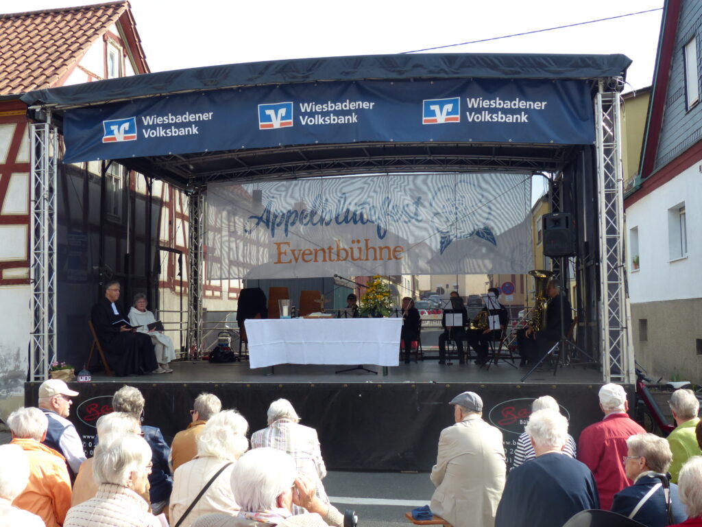 Foto mit Festbühne und den davor sitzenden Menschen