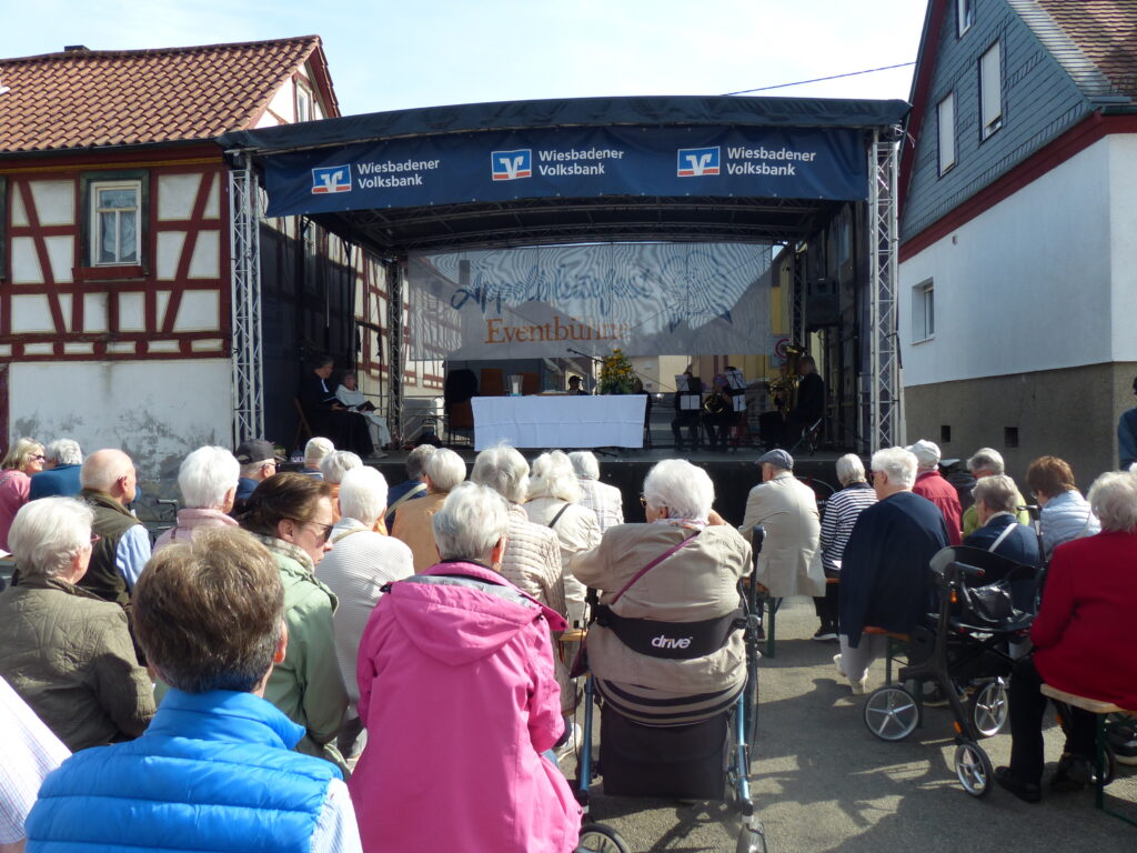 Foto mit Festbühne und den davor sitzenden Menschen