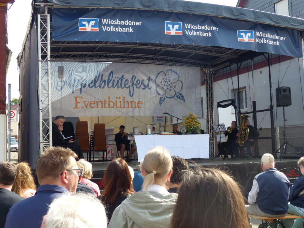 Foto mit Festbühne und den davor sitzenden Menschen