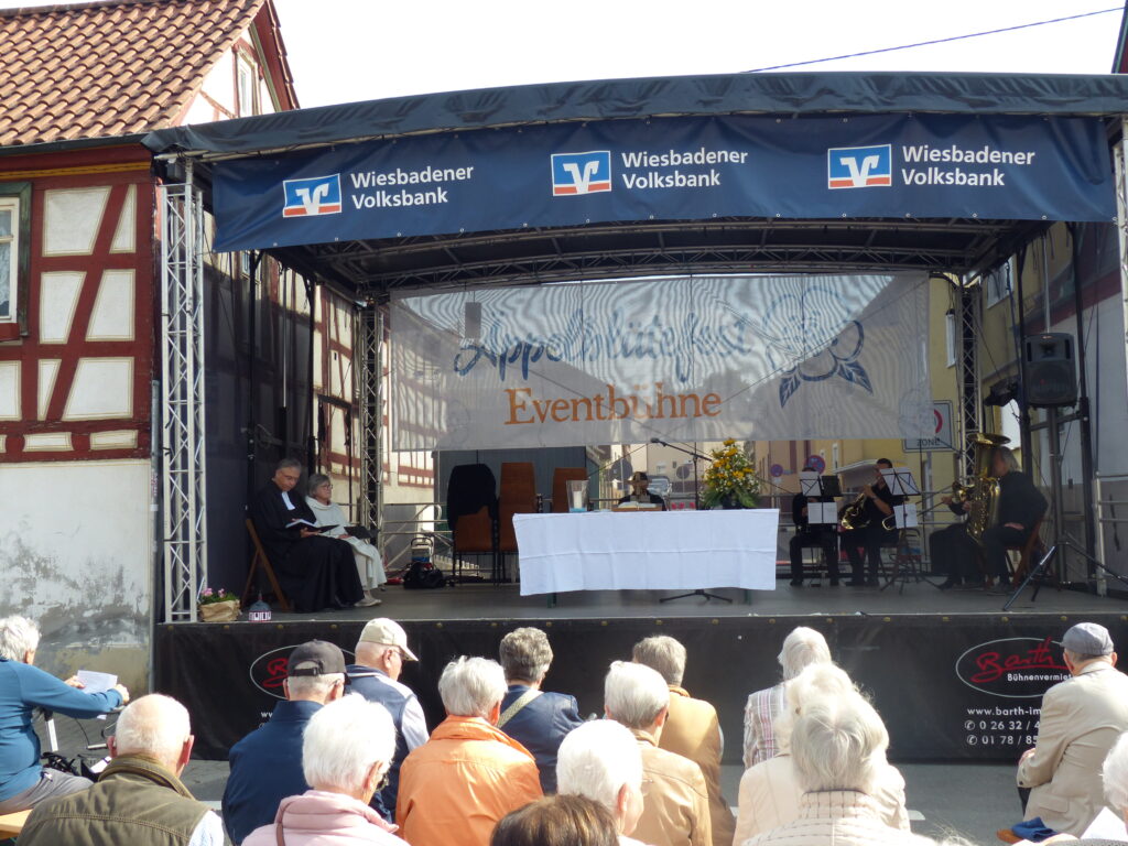 Foto mit Festbühne und den davor sitzenden Menschen