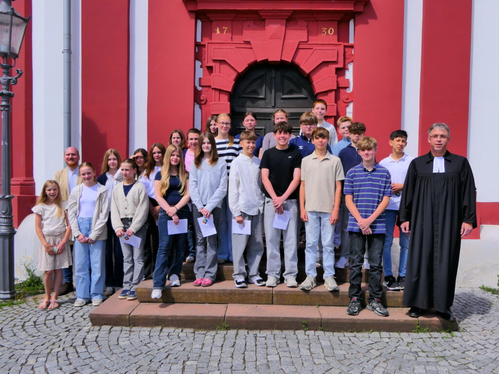 Die Konfirmandinnen und Konfirmanden stehen gemeinsam mit Pfarrer Ebling und Pfarrer Tschöpel auf der Kirchentreppe.