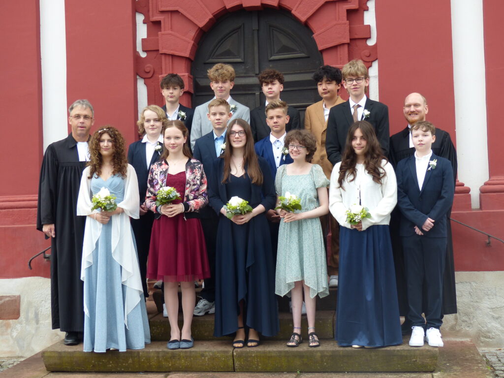 Die Konfis stehen mit beiden Pfarrern zu einem Gruppenbild auf der Treppe vor der Kirche.